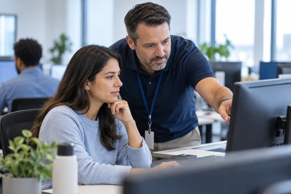 An IT support professional helping a colleague at an office workstation